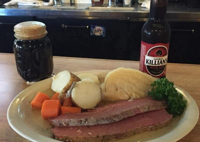 Corned beef dinner with boiled potatoes, carrots, cabbage and George Killian's Irish Red beer on wooden table