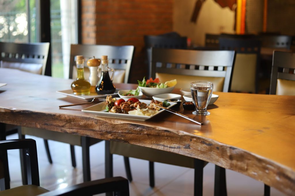A charming view of a rustic dining table set with a delicious meal and condiments in a cozy restaurant interior.