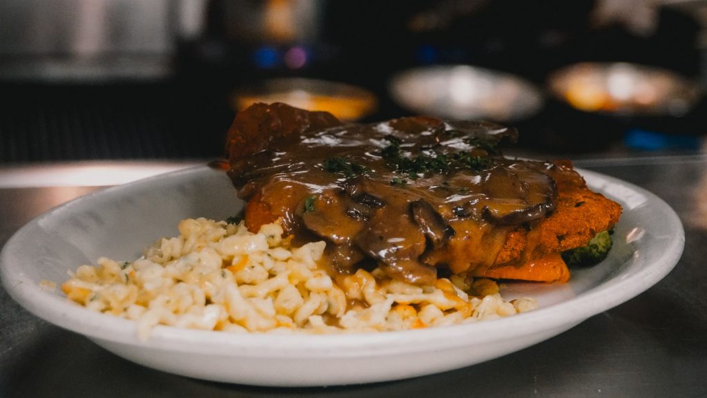 A close-up of schnitzel with creamy mushroom sauce served with pasta, perfect for gourmet dining.