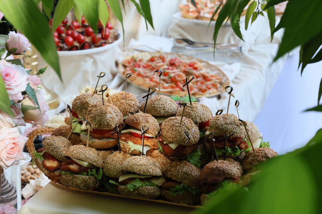 A delightful spread of sandwiches and pizzas at an elegant party setting, surrounded by flowers and greenery.