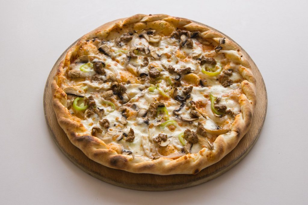 A mouthwatering close-up of a pizza with toppings, baked on a wooden board.