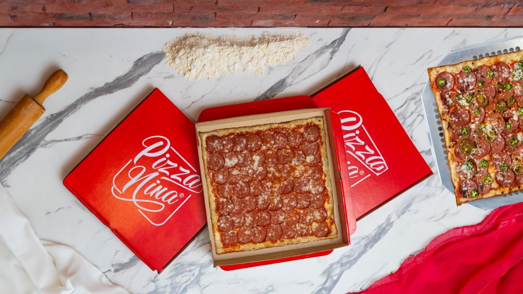 A mouthwatering pepperoni pizza in a red box with a vibrant flat lay composition.