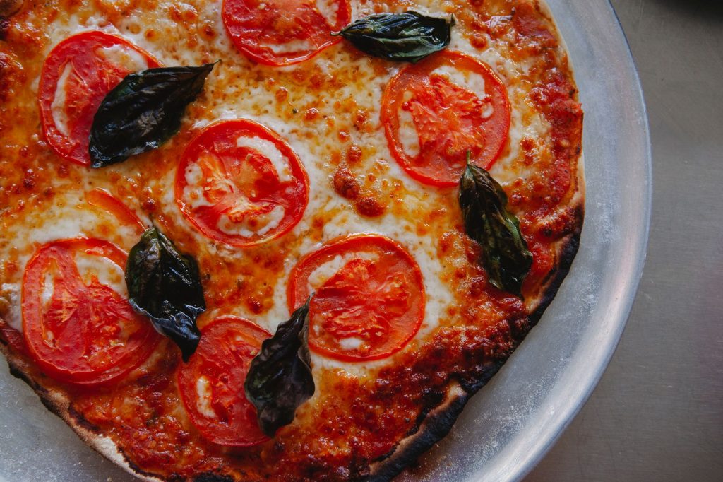 Close-up of a delectable margherita pizza topped with fresh basil, mozzarella, and tomato slices.