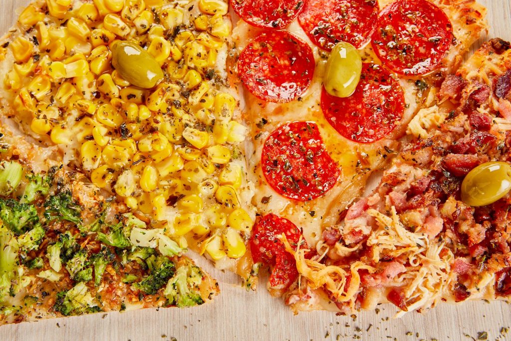 Close-up of a four-flavored pizza with corn, pepperoni, broccoli, and bacon toppings, vibrant and delicious.