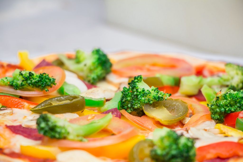 Close-up of a freshly prepared vegetarian pizza topped with colorful vegetables.