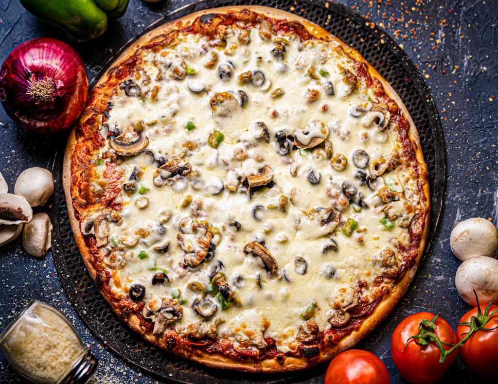 Close-up of a mushroom and cheese pizza with ingredients, perfect for Italian cuisine lovers.