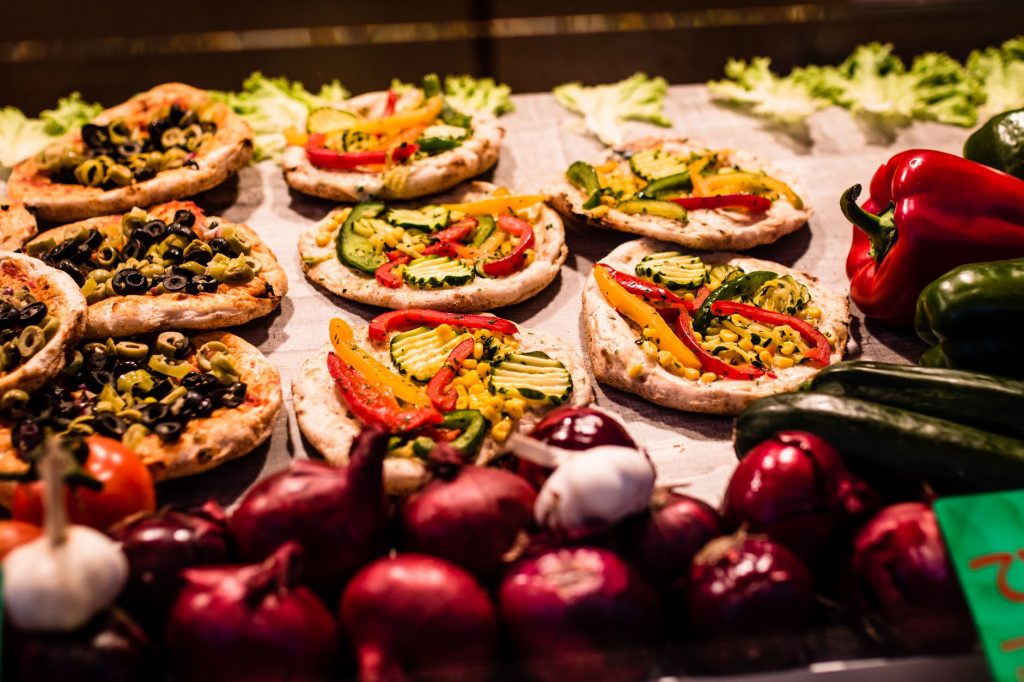 Close-up of colorful mini vegetable pizzas surrounded by fresh ingredients, showcasing food diversity.