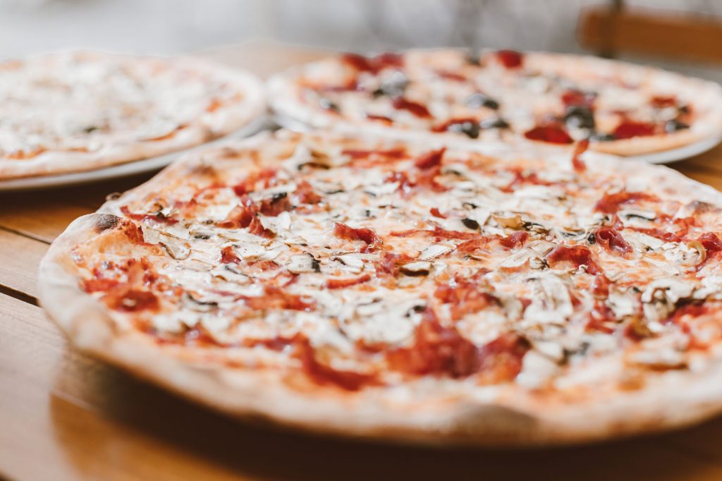 Close-up of freshly baked pizzas with mushrooms served on a wooden table.