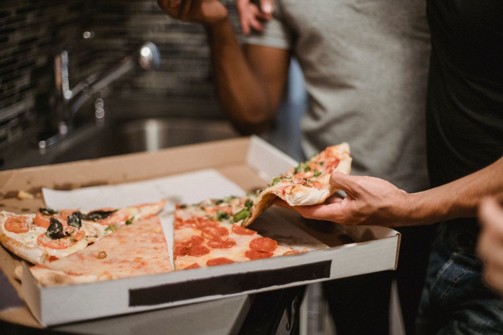 Close-up of friends sharing a pizza, showing diverse toppings and human interaction.