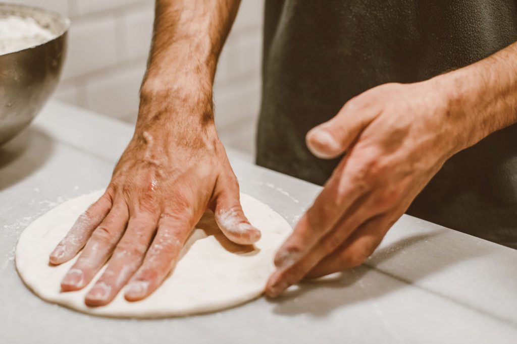 Close-up of hands shaping pizza dough, capturing the art of cooking.