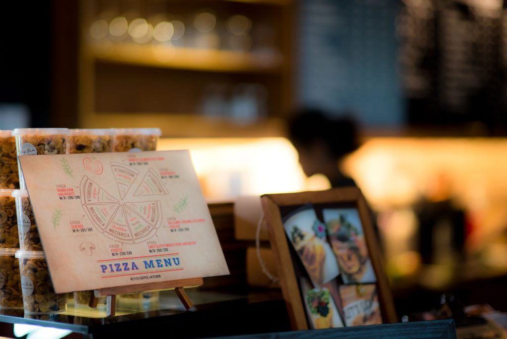 Close-up view of a pizza menu displayed in a warmly lit restaurant setting.