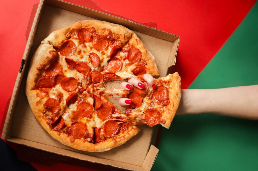 Fresh pepperoni pizza being pulled from the box. Perfect comfort food moment.