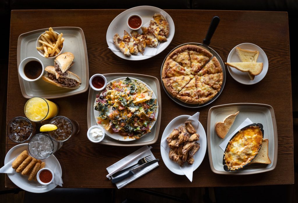 Top view of an assorted meal platter featuring pizza, nachos, wings, and more.