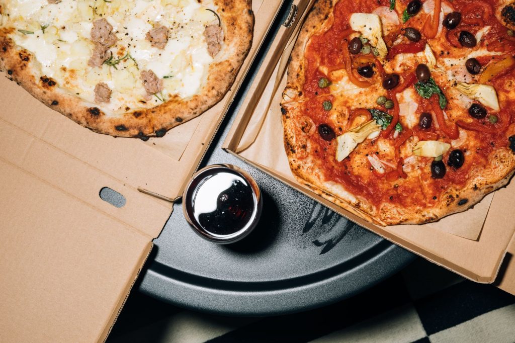 Top view of delicious pizzas in boxes with a refreshing drink, perfect for a cozy meal.