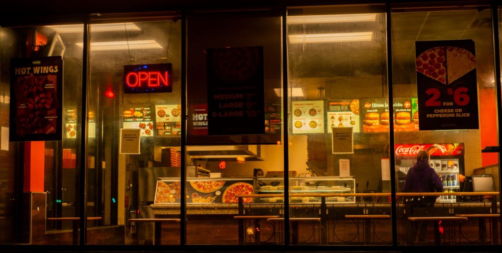 Warm view of a pizza restaurant through the glass window at night, Barrie, ON.